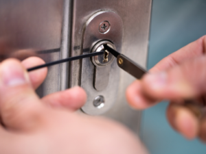 Close-up of hands picking a door lock using lockpicking tools, demonstrating skilled techniques often used in residential locksmith services.